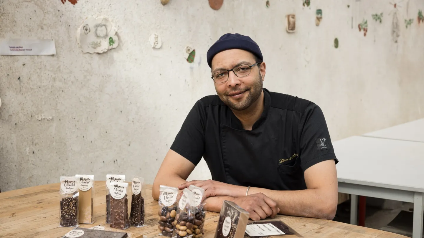Mahdi Borgi assis à une table avec ses chocolats présentés devant lui