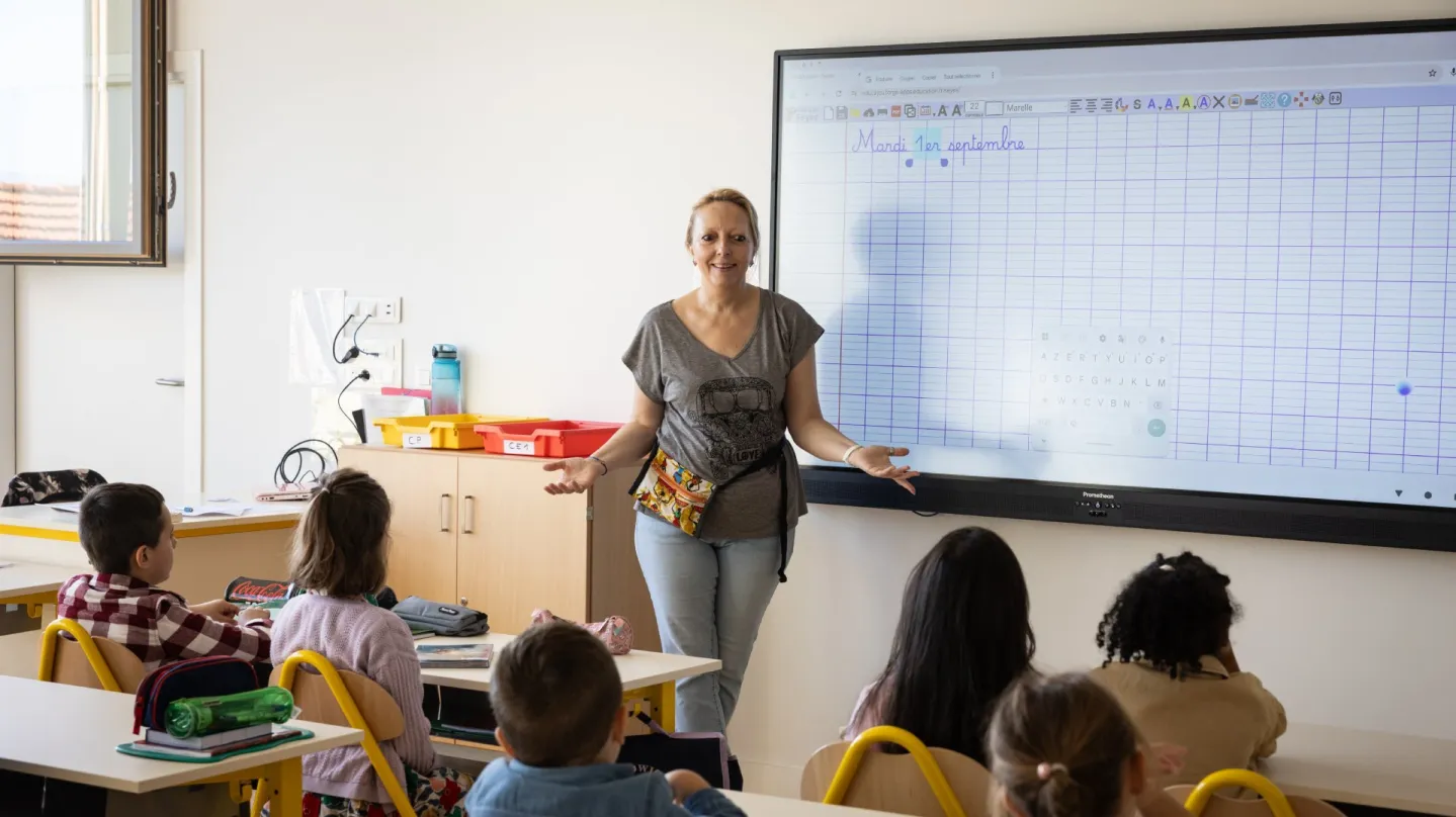 Une professeure debout face à ses élèves en classe d'élémentaire